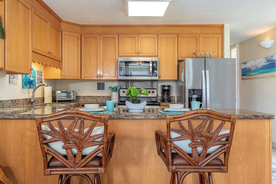Gather around the granite breakfast bar where coastal charm meets convenience. Enjoy your morning coffee in this fully-equipped kitchen, complete with modern appliances and island seating for easy meals together.