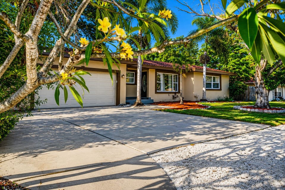 Bright exterior view with ample driveway space and lush Florida landscaping.