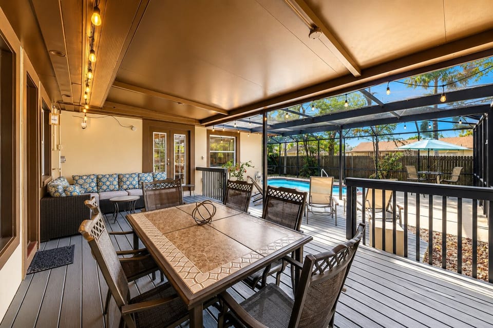 Large outdoor entertaining space with dining table, lounge seating, and screened enclosure.