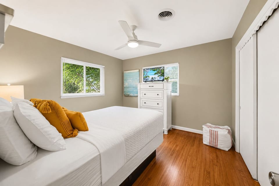 Spacious guest room with a dresser, TV, and calming neutral décor for a restful stay.