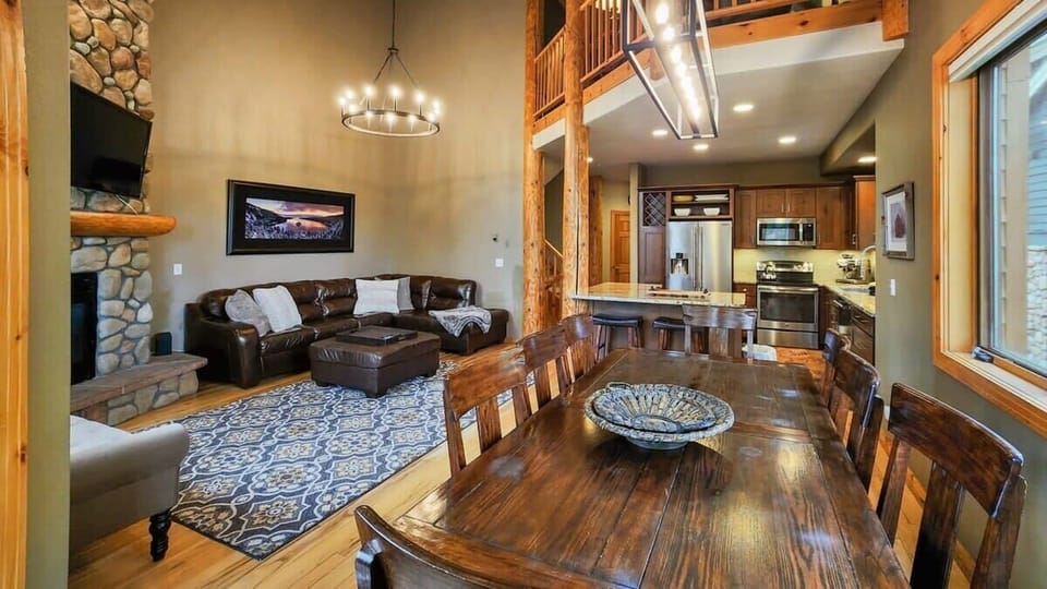 The view over the main living space where you will find the kitchen/dining/living room with soaring windows overlooking the trees, vaulted ceilings, and stylish furnishings.