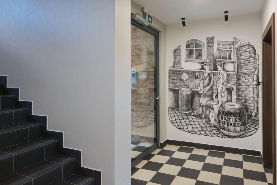 A stylish staircase area with artistic wall decor and checkered flooring, blending creativity with design.
