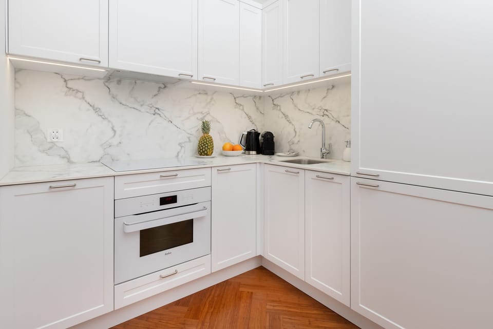 A modern kitchen with white cabinetry, marble-style backsplash, and built-in appliances for a sleek, clean look.
