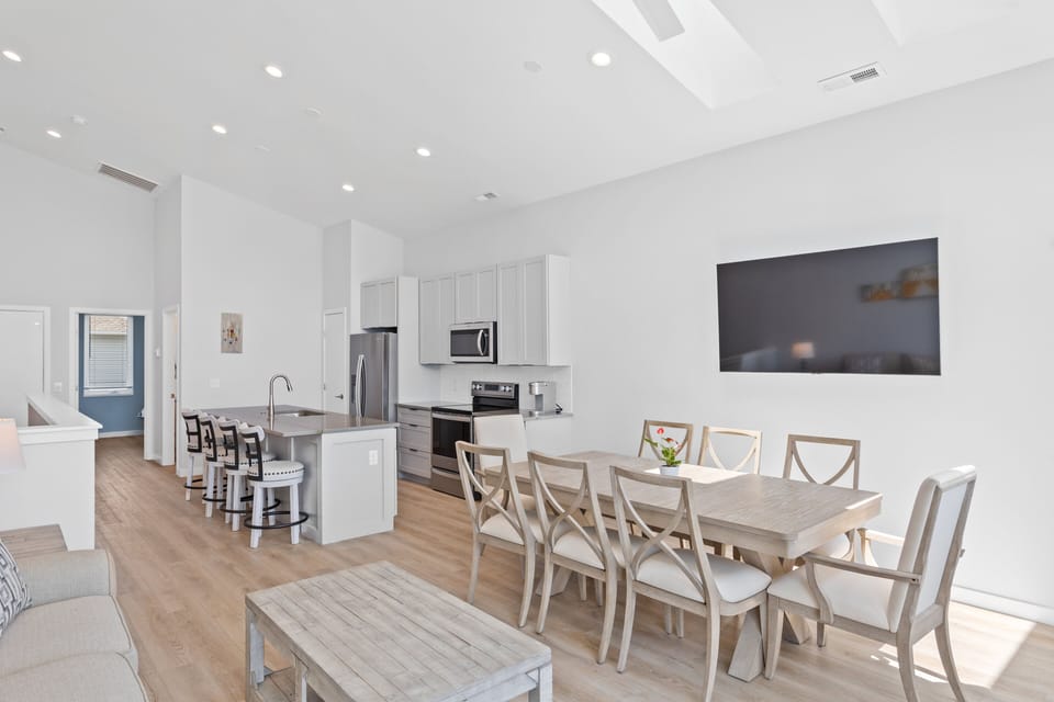 The open living, kitchen, and dining areas with a Smart TV and balcony access