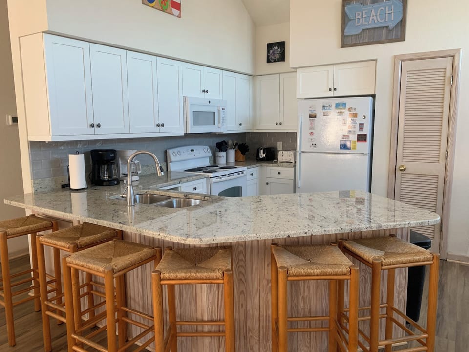 Breakfast bar - Well-appointed kitchen featuring granite countertops, white appliances, and a breakfast bar, ideal for preparing home-cooked meals