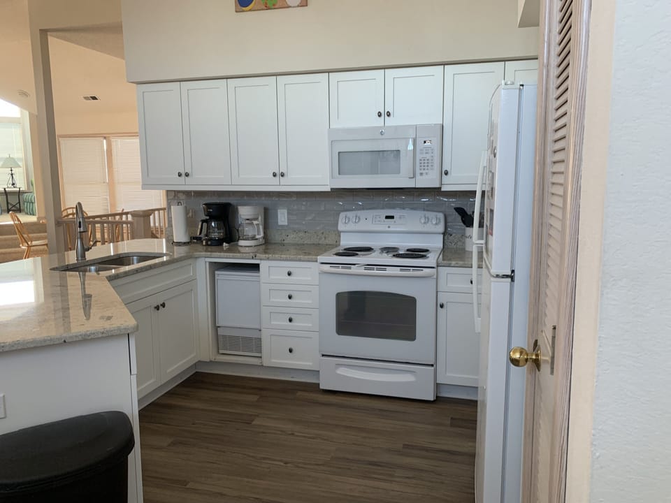 Kitchen - Well-appointed kitchen featuring granite countertops, white appliances, and a breakfast bar, ideal for preparing home-cooked meals