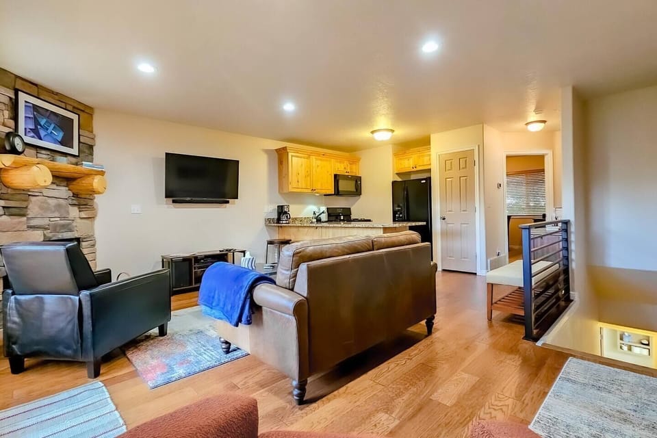 The living room, appointed with comfortable furniture, offers easy access to the outdoor deck, as well as the stairway to the bedrooms on the lower level.