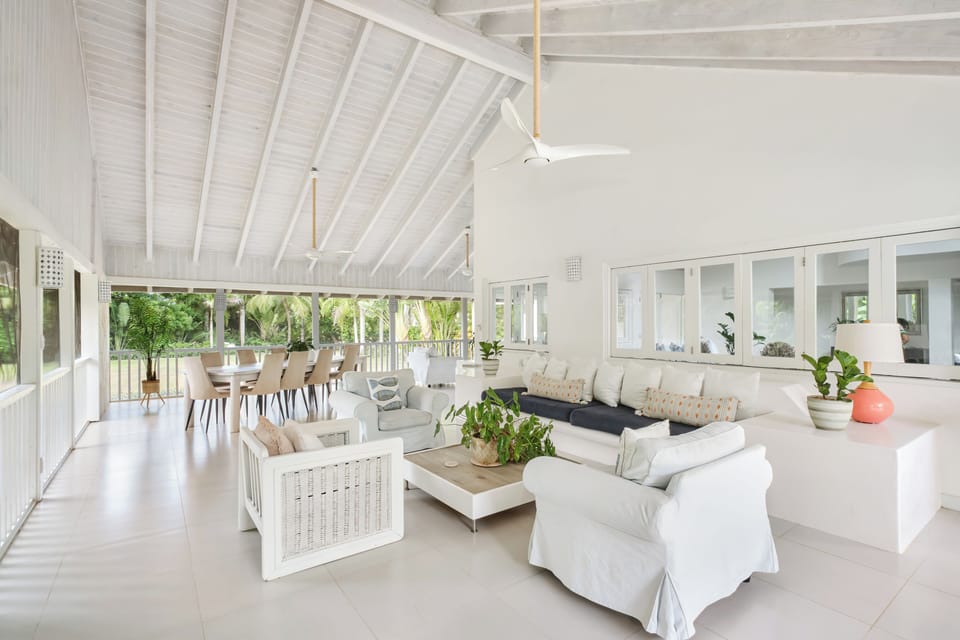 Wrap-around screened patio with large dining table with view of garden and pool