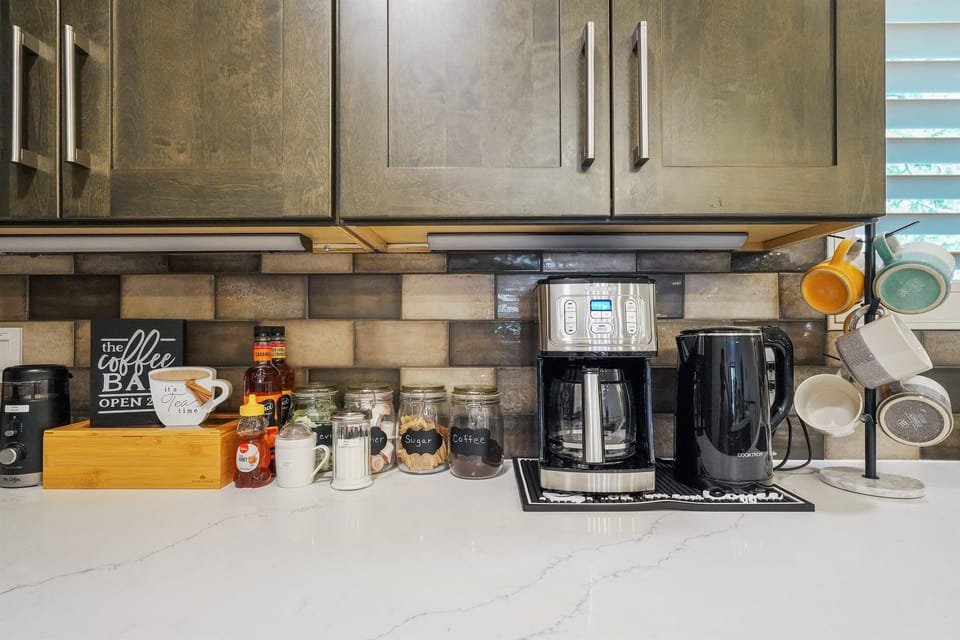 Coffee station with 12-cup coffee maker, grinder, and electric kettle.