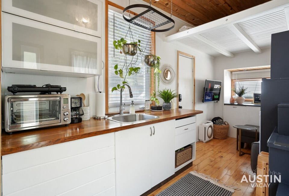 Kitchen with hot plate, toaster oven, coffee machine, and refrigerator.