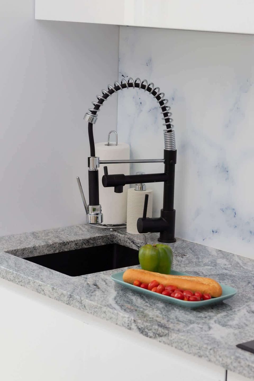 A modern kitchen sink with a sleek black faucet and a marble countertop, offering both style and functionality.
