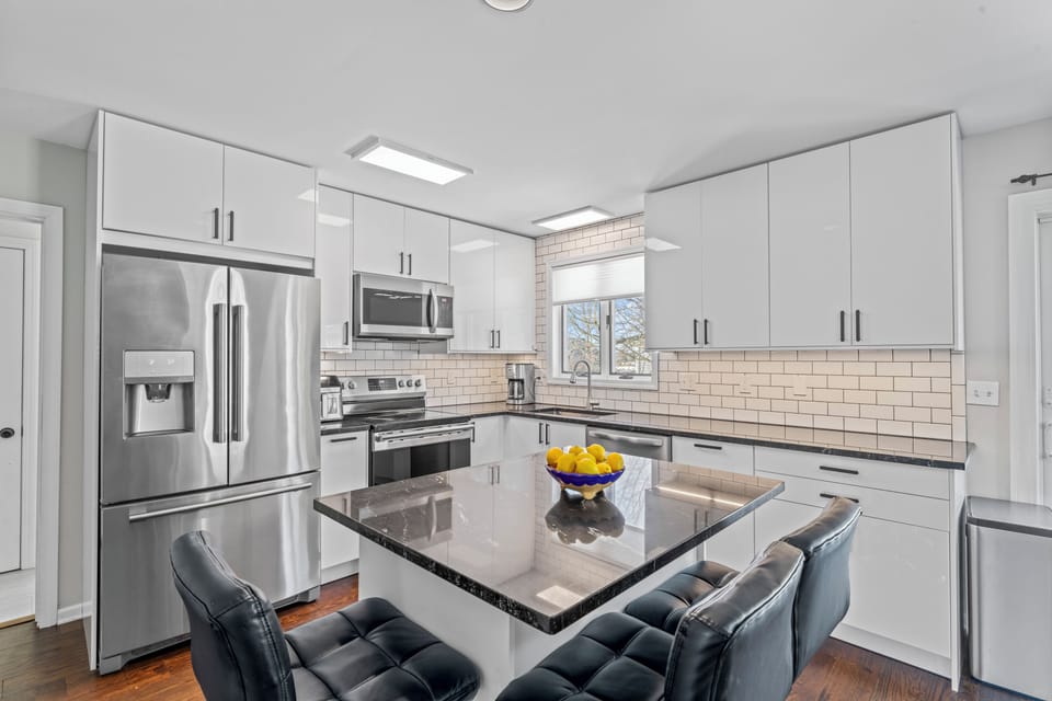 Updated coastal kitchen with stainless steel appliances, island seating, and eve
