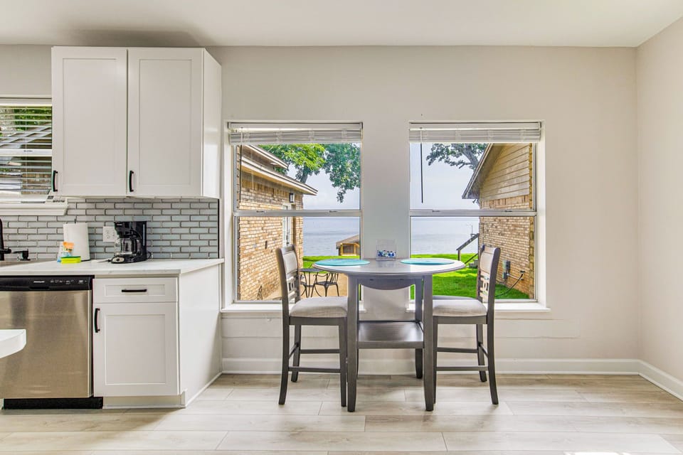 Bright dining area with bay views connects to kitchen at Bayfront Bliss Gulf Breeze bayfront vacation rental