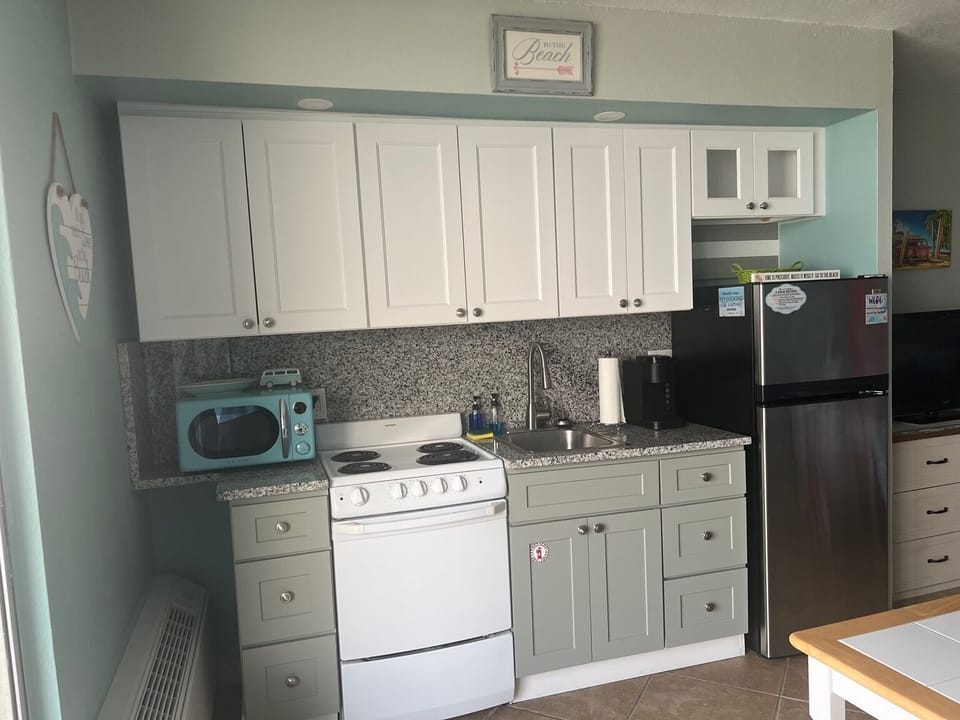 Renovated kitchen with new cabinets, countertop, backsplash, and lighting.