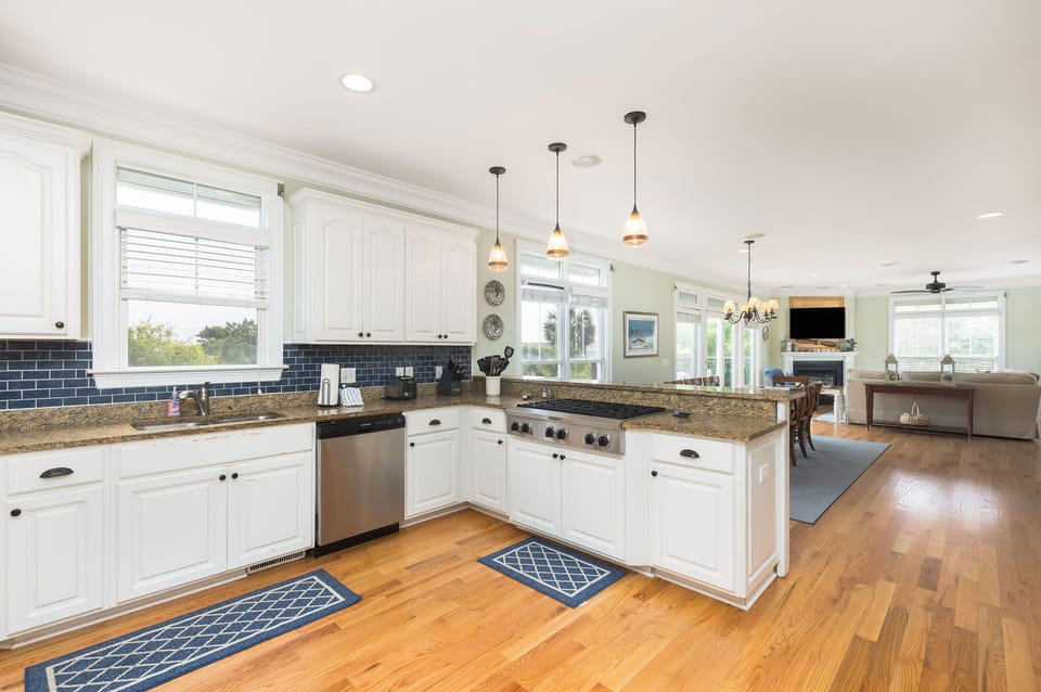 White cabinetry, stainless steel appliances, and modern pendant lighting create an inviting space to cook fresh seafood.