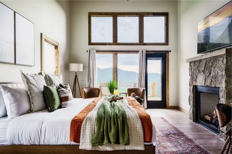 [Master's Bedroom]- Indulge in luxury in this spacious master bedroom on the upper level, with a cozy fireplace, large TV, and breathtaking mountain views. 