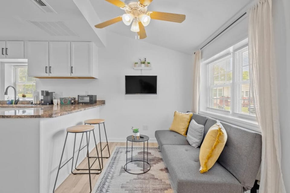 Bright, open-concept living space with Roku Smart TV & cozy seating.  Kick back and stream your favorite shows in this sunlit lounge, complete with ceiling fan and seamless flow into the kitchen and dining area.