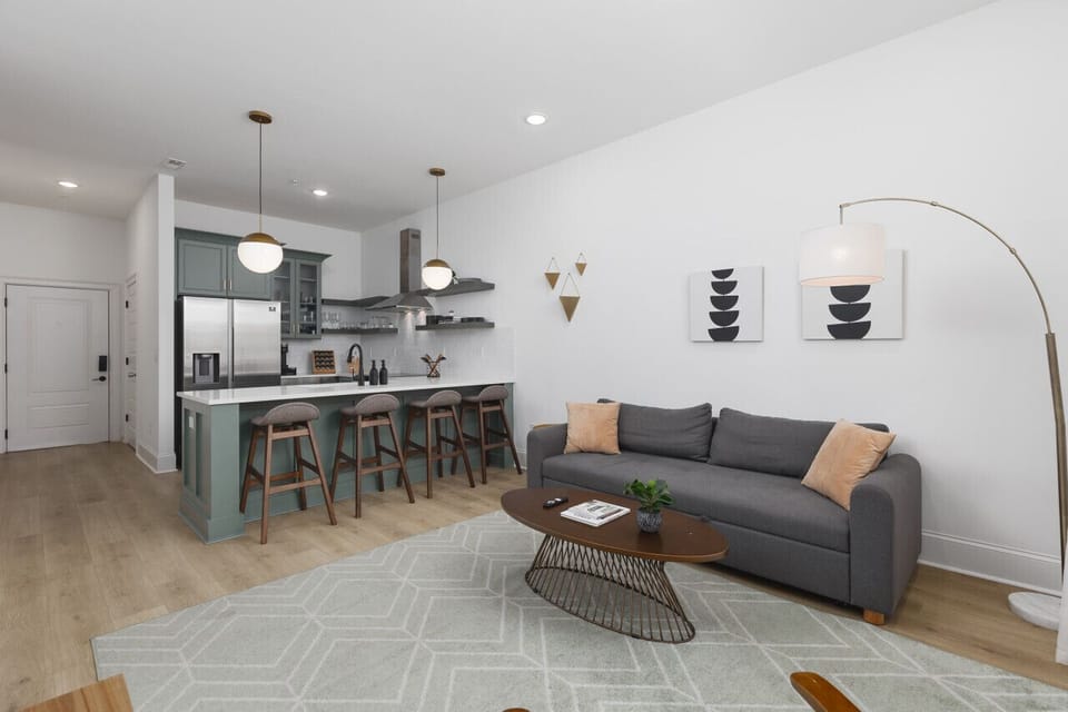 Living room with a full-size sleeper sofa, a Smart TV, plenty of natural light, and thoughtful decor. Open floor plan leads from this space into the kitchen.