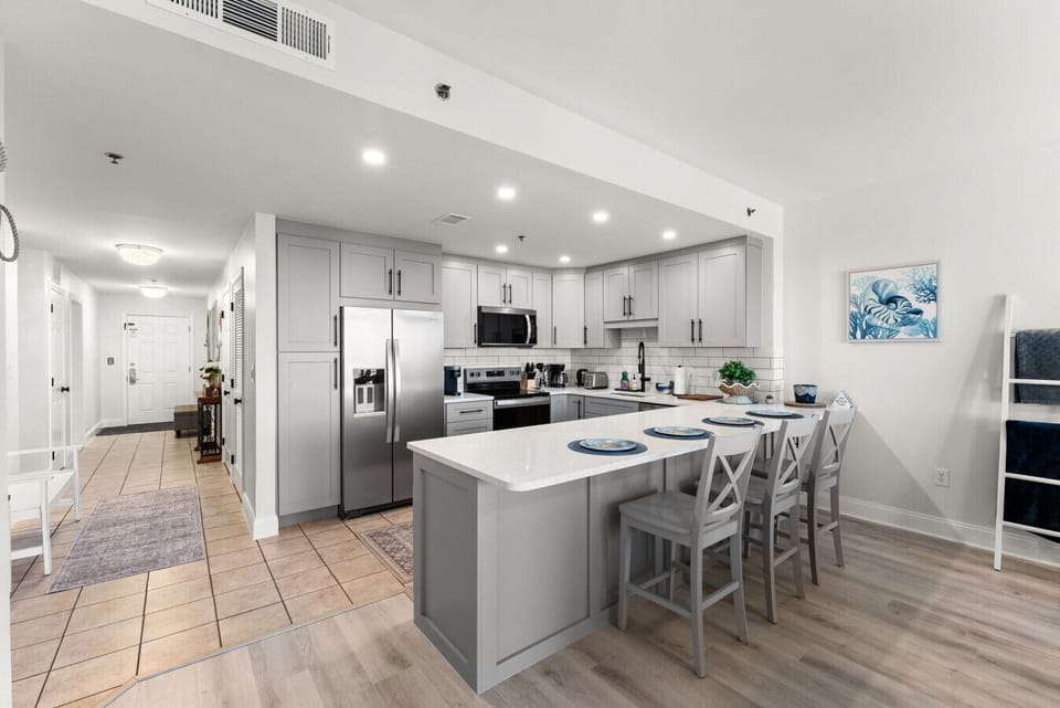 Modern, fully renovated kitchen showcases stainless-steel appliances, quartz counters, and seating for four at the spacious island.