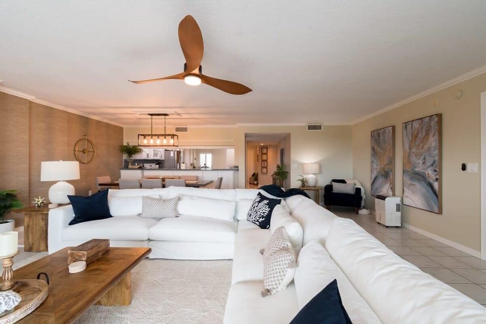 Spacious living area with a large white sectional sofa and modern ceiling fan.