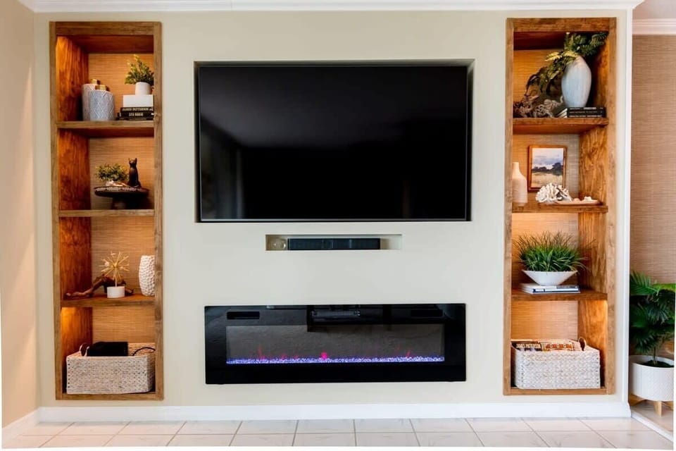 Modern entertainment wall with a mounted flat-screen tv and built-in electric fireplace.