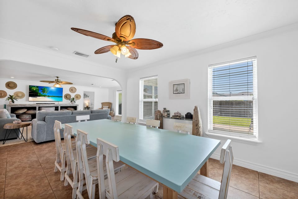Gather around your spacious glass dining table for memorable meals while tropical ceiling fans create the perfect coastal breeze overhead.
