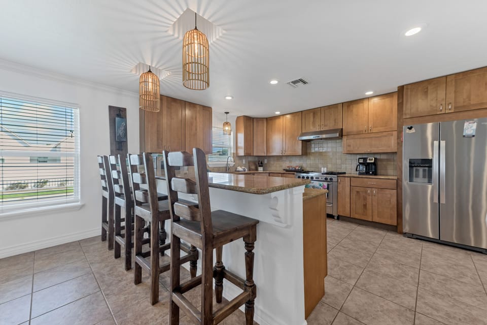Your spacious kitchen features warm wood cabinetry, granite countertops, and a breakfast bar perfect for morning coffee conversations.