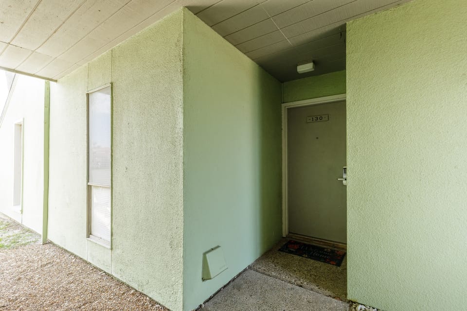 Property entrance with mint green exterior walls and covered walkway leading to unit 130.