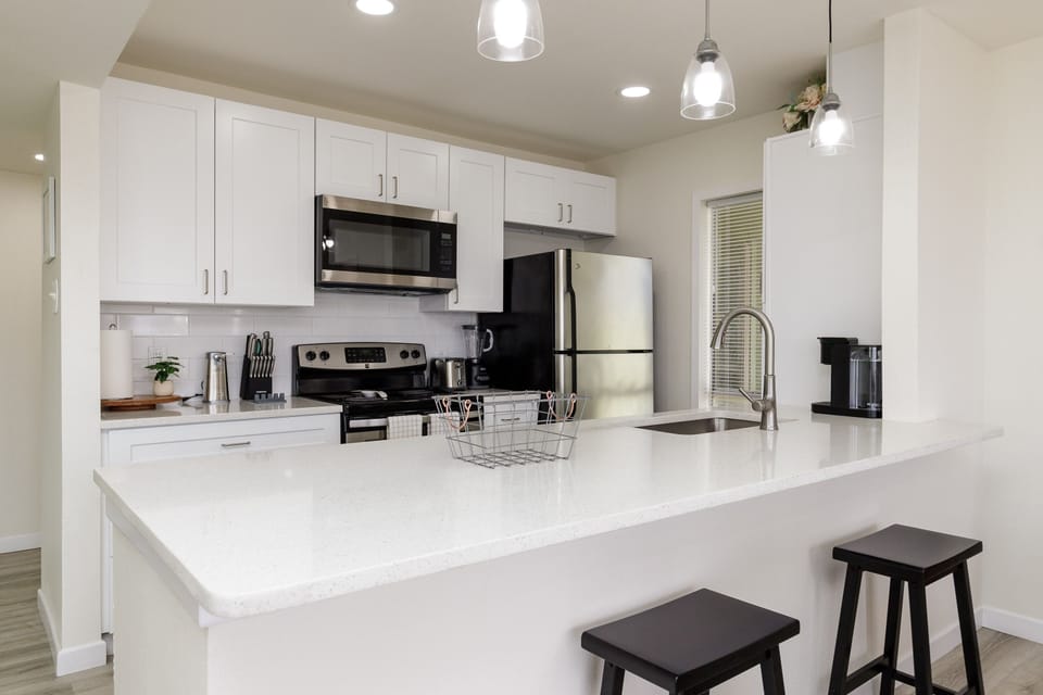 Your modern kitchen features sleek white cabinets, stainless appliances, and a spacious island perfect for cooking and casual dining.