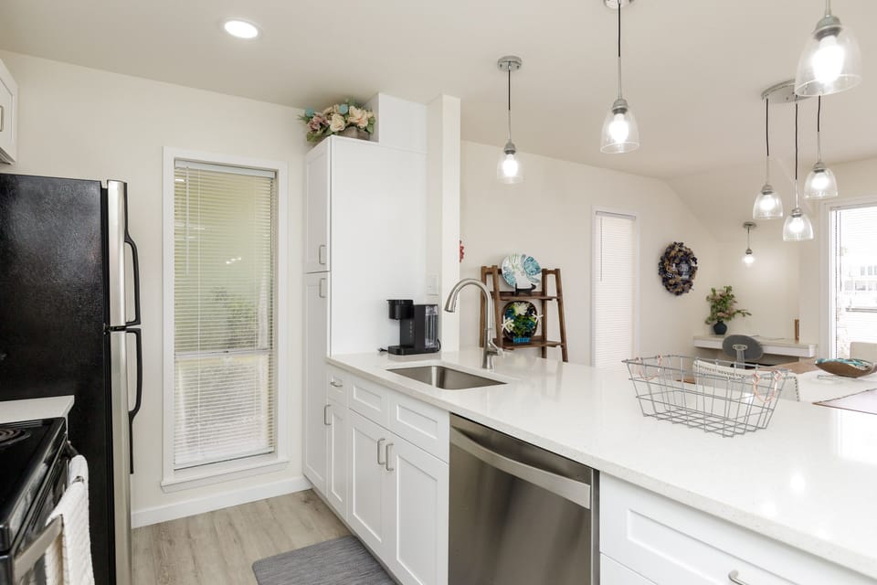 Your bright, modern kitchen awaits with gleaming white counters, stylish pendant lighting, and everything needed for memorable meals.