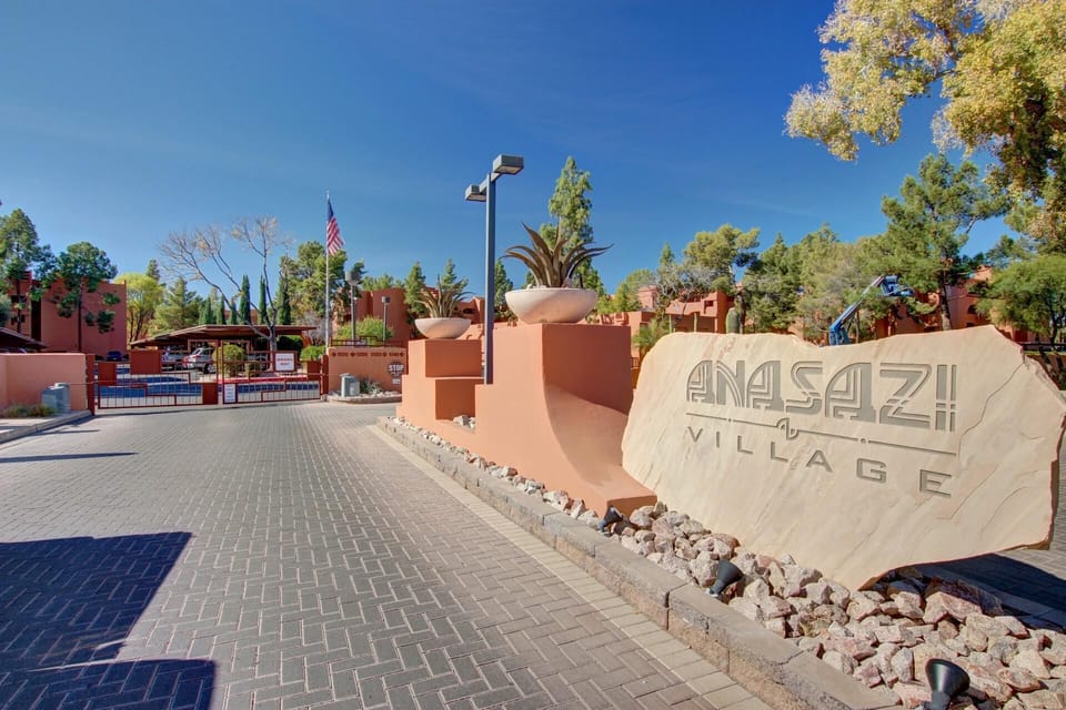Paved entrance road leads to gated access with terracotta walls and large engraved stone sign.