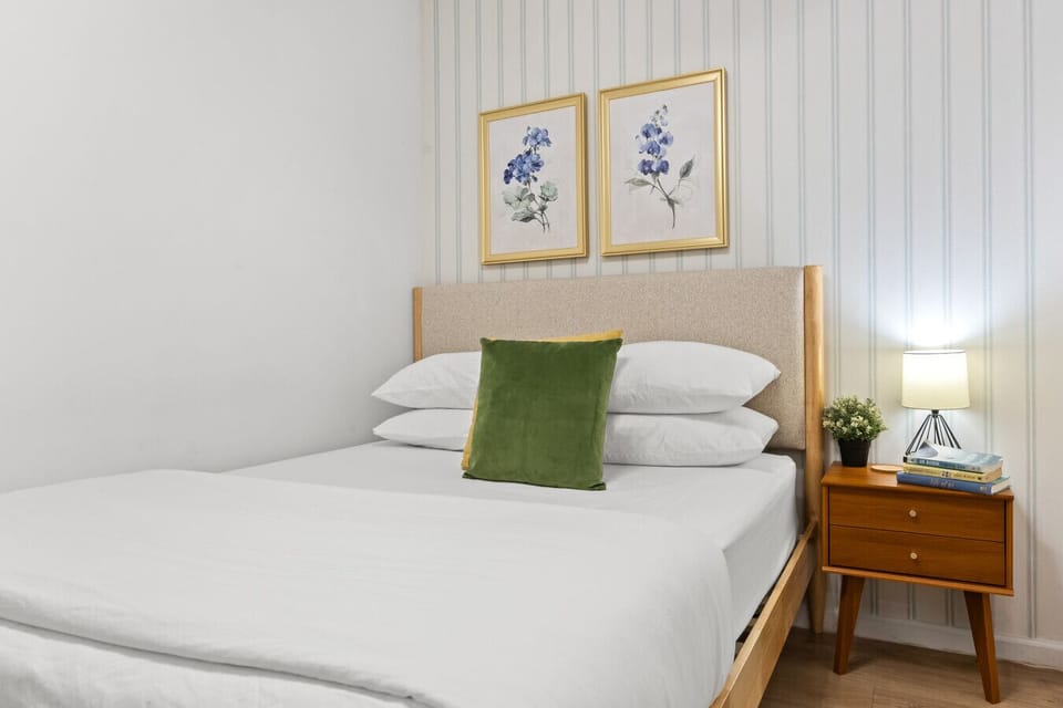 A beautifully styled nightstand adds warmth to the second bedroom, complete with a soft bedside lamp, books for relaxing, and a small plant to brighten the space.