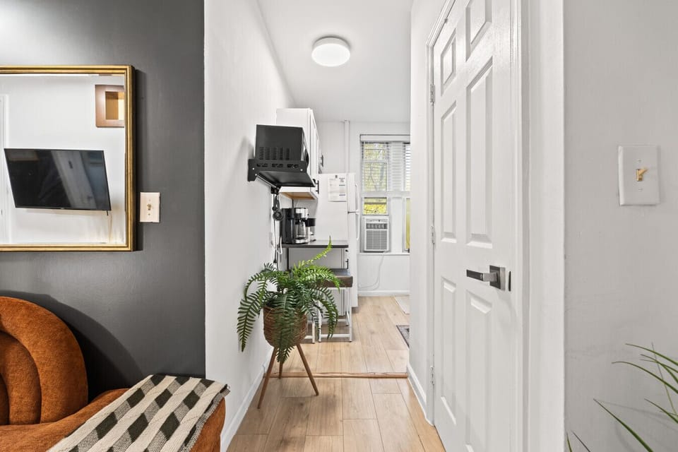 This hallway connects the living room to the kitchenette, where you’ll find a full fridge, coffee setup, and cooking essentials.