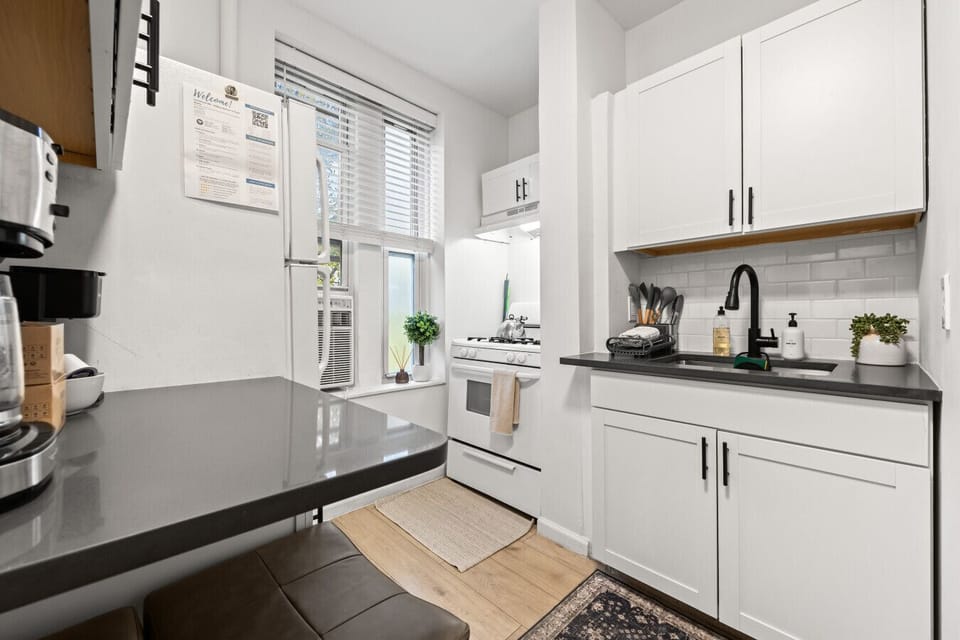 A well-equipped kitchenette featuring a gas stove, cooking essentials, dish rack, and coffee setup, all in a bright, functional space.