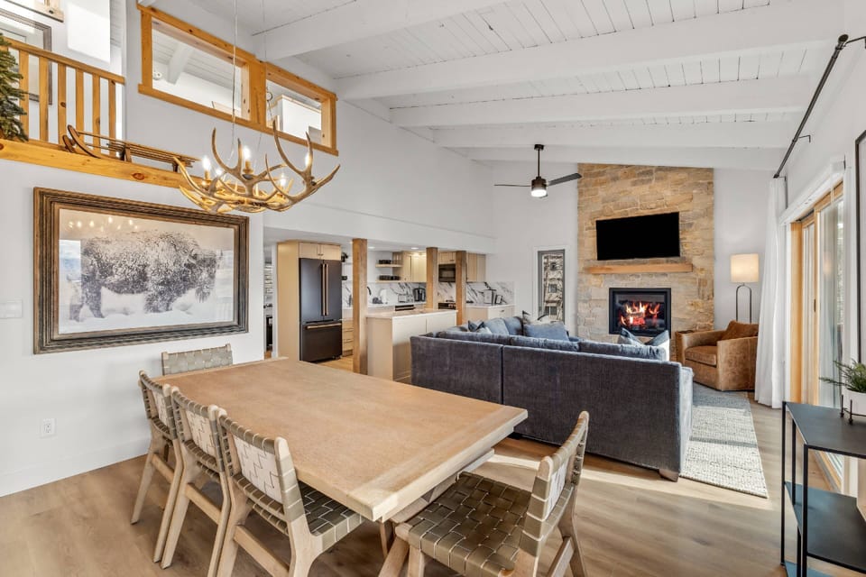 Warm, modern mountain living space with a cozy fire, large dining table, and plenty of room to gather