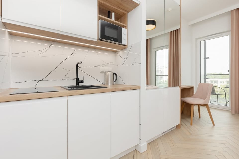 A bright kitchen with white cabinetry, wooden countertops, and essential appliances for convenient cooking.
