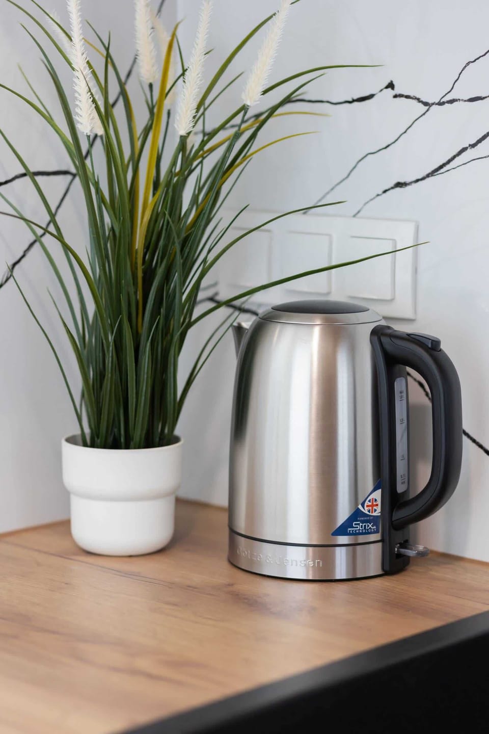 A close-up of the kitchenette counter with a kettle and decorative greenery for added charm.

