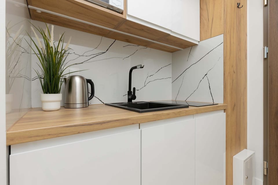 A view of the kitchenette featuring wooden accents, a sink, and modern appliances for convenience.
