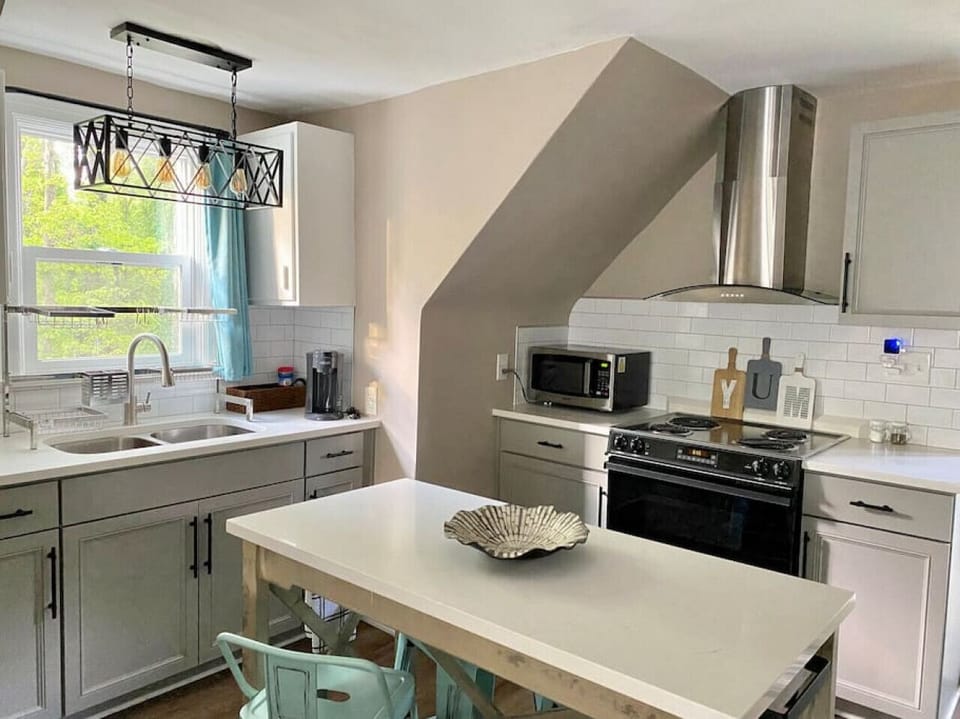 Fully stocked kitchen with quartz countertops and the custom built kitchen island also serves as dining table with quartz top to match.  Range, hood, microwave, retro powder blue fridge matches the dining chairs and accents throughout.