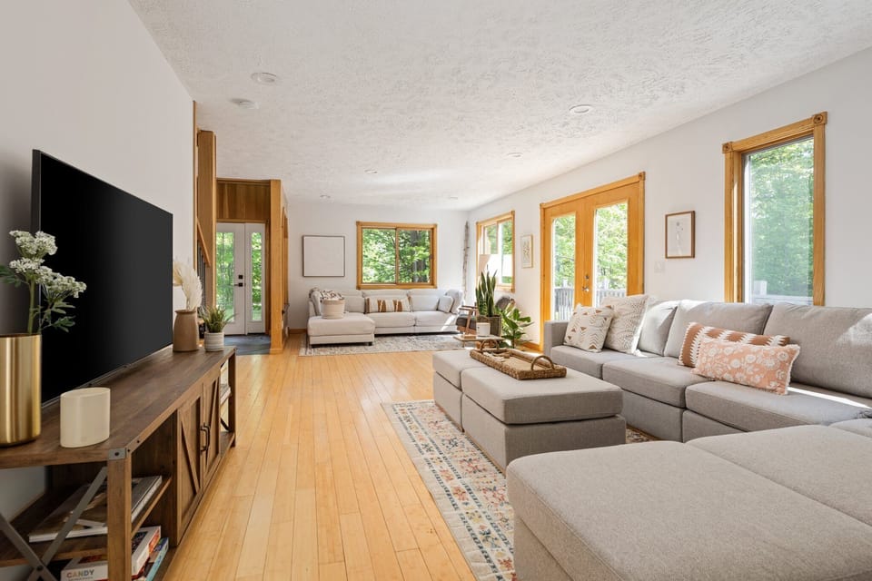 Bright living room w/ plush sectional, large windows & warm wood floors for laid-back evenings