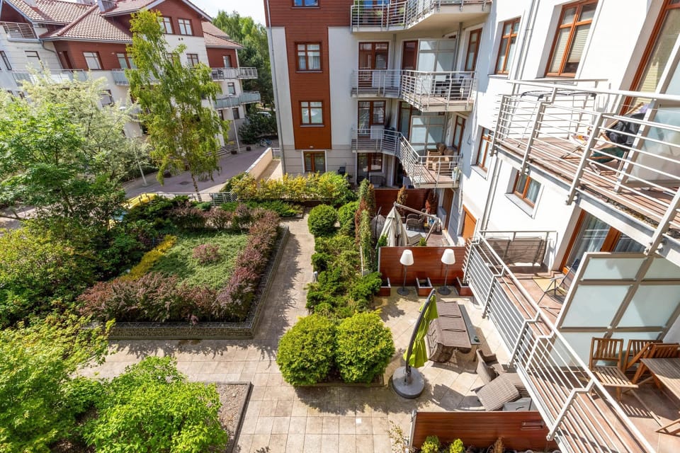 A picturesque view of a green courtyard surrounded by modern residential buildings and charming balconies.
