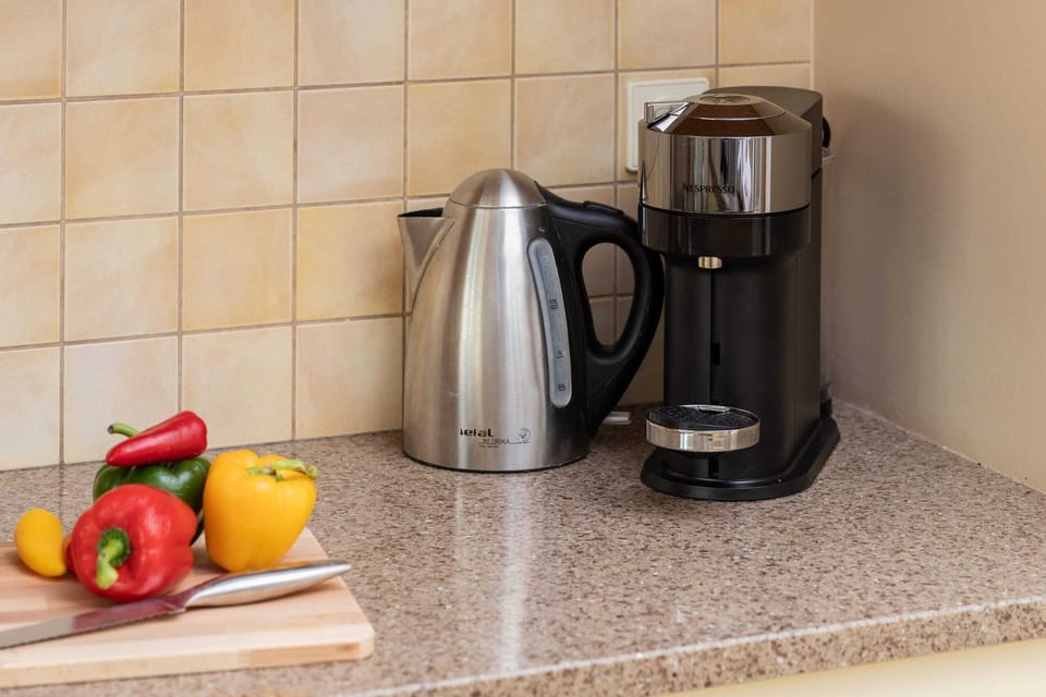 A kitchen countertop with a coffee maker, kettle, and fresh fruits, emphasizing functionality and charm.
