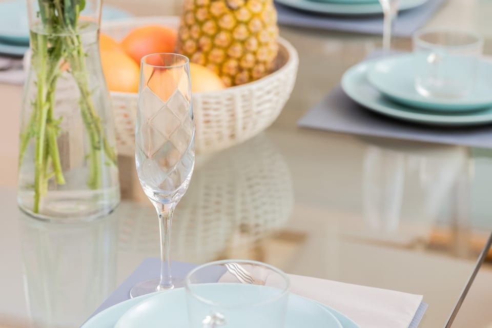 A close-up of a dining table set with a fruit centerpiece, plates, and elegant glassware.
