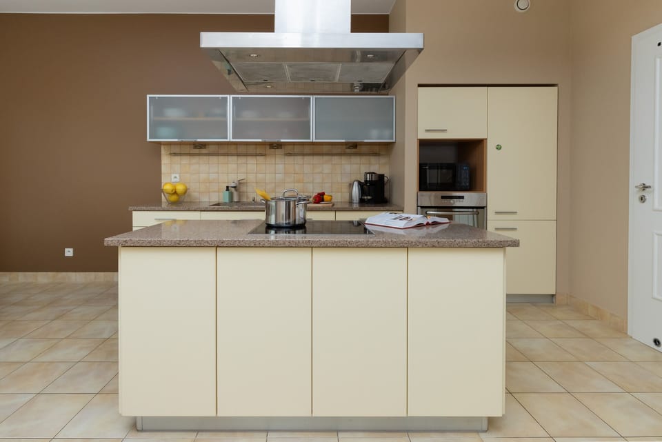 A modern kitchen with a central island, ample cabinetry, and stainless steel appliances.
