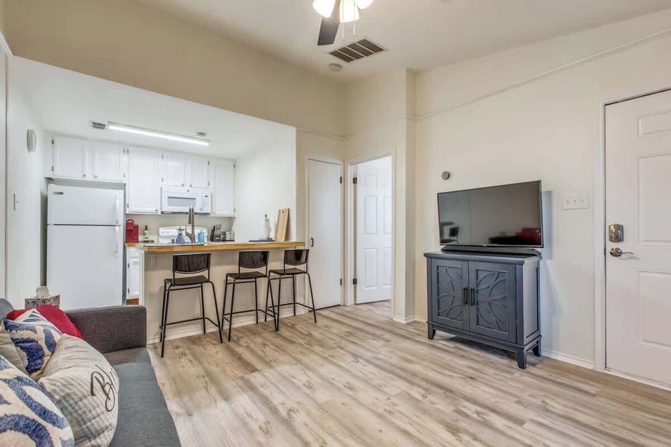 Cozy living room with an open layout, featuring a comfy seating area, smart TV, and a convenient kitchenette with bar-style dining.