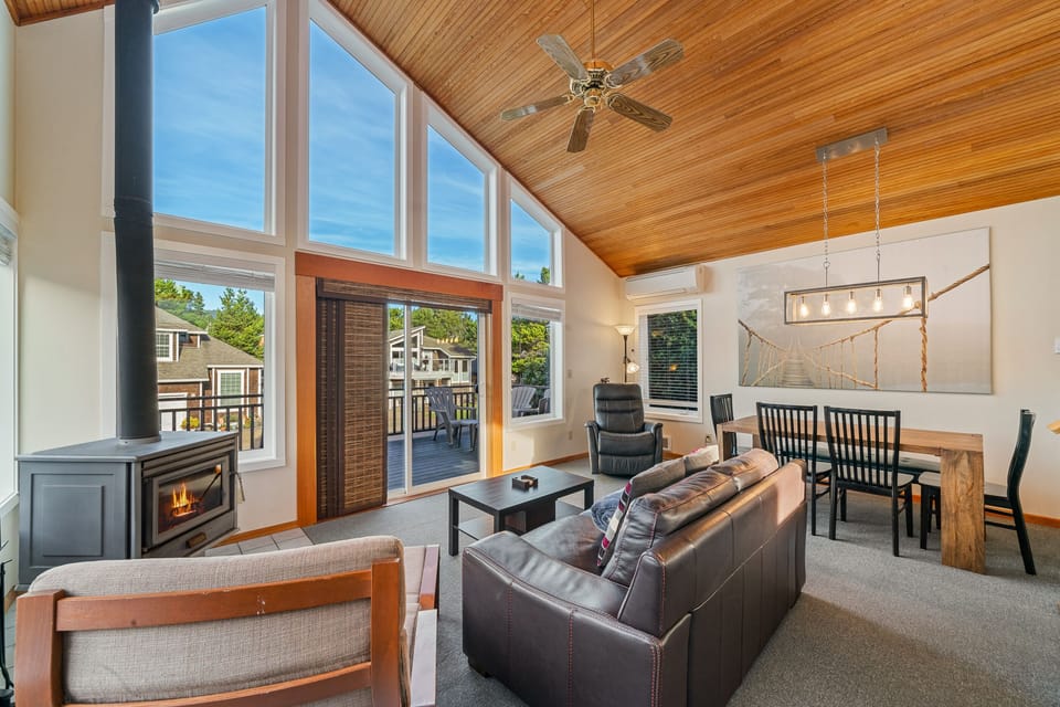 Living/dining room with woodstove and access to front deck with BBQ and outdoor furniture.