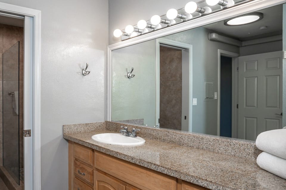 Refresh in your private bathroom with bright vanity lighting, a granite countertop, and plush towels waiting for you after a warm shower.