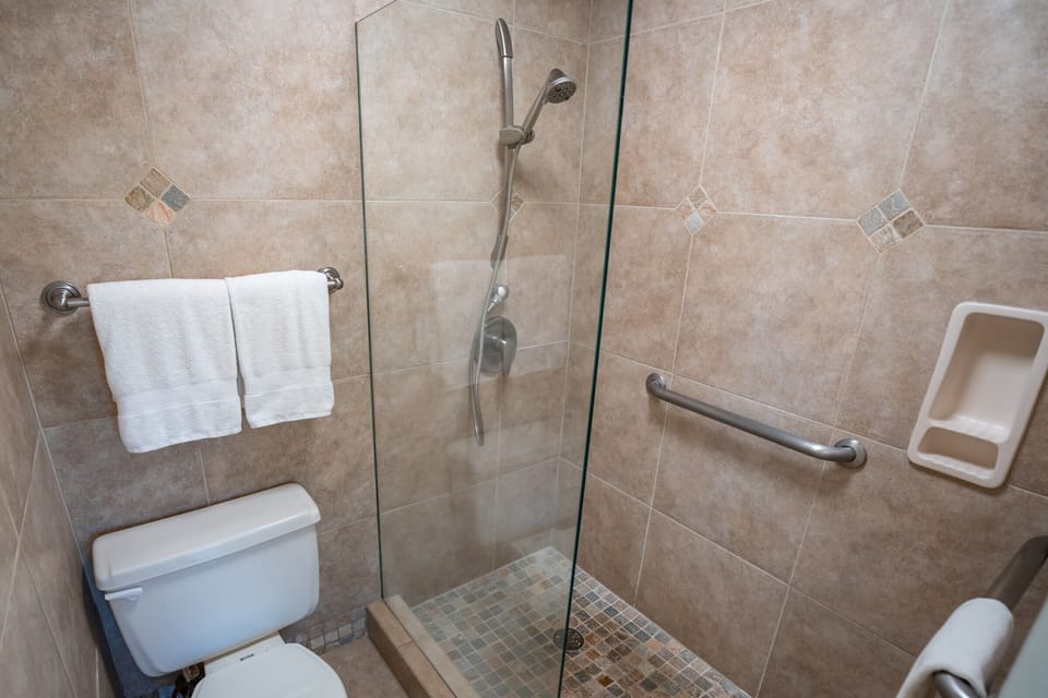 Step into your spacious walk-in shower with convenient grab bars and handheld showerhead for a safe, comfortable bathing experience.