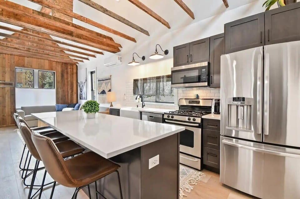 The fully equipped kitchen is complete with stainless steel appliances, a full range of cooking essentials, and a large kitchen island with four bar stools.