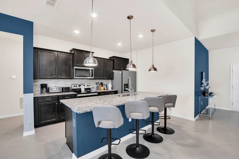 Modern kitchen featuring a spacious island with sleek bar stools—perfect for casual dining and family gatherings. Ample counter space and stylish cabinetry create a warm, welcoming atmosphere for cooking and entertaining.